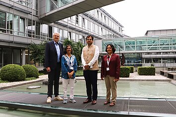 Four people stand in the courtyard of IFW Dresden in front of a reflecting pool. From left to right: Prof. Dr. Bernd Büchner, Dr. Kusumita Arora, Sohag Sen, and Prof. Dr. Tanusri Saha-Dasgupta.